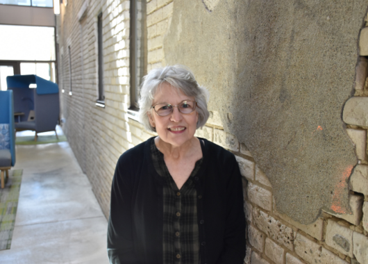 Older woman in a black blouse at a brick wall